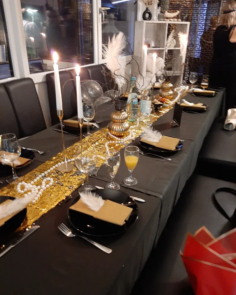 Festlich gedeckte Tafel in Schwarz und Gold mit Kerzen und weißen Federn