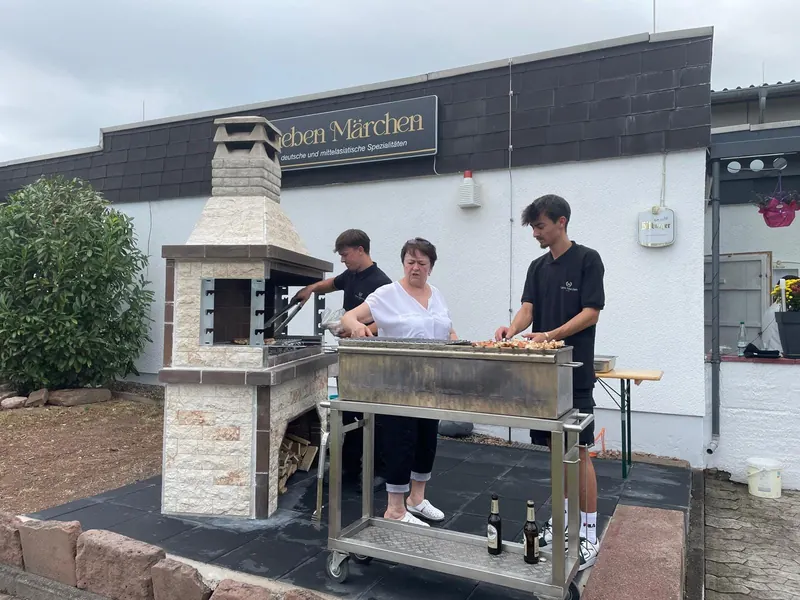 Die Familie grillt Schaschlik am Mangal vor dem Restaurant