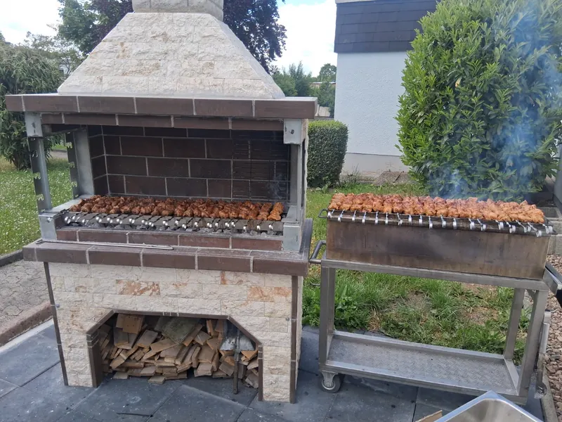 Gemauerter Grillofen mit Feuerholz und Schaschlik auf dem Rost