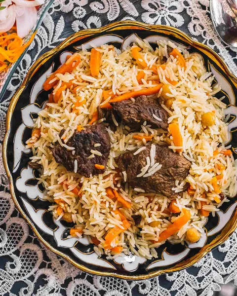 Plov mit Reis, Fleisch und Möhren auf einer bemalten Keramikplatte