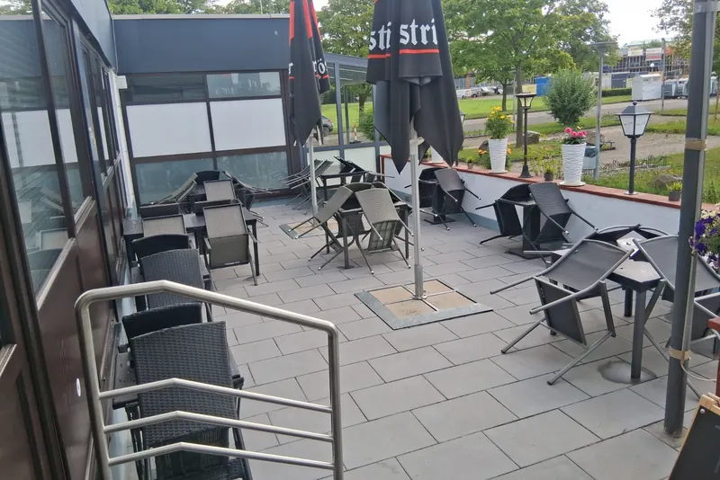 Die Terrasse mit Tischen und Sonnenschirmen