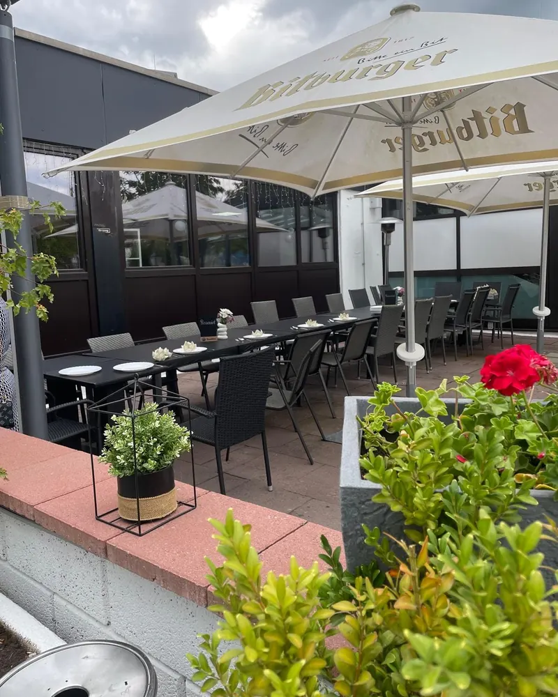 Lange Tafel für eine Gesellschaft auf der Terrasse, unter Sonnenschirmen